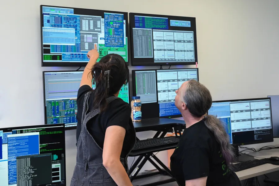 Coronagraph Operators Amelia Nash and Judy Adler monitor telemetry on a wall of six monitors inside the Roman Coronagraph Commanding Center at IPAC at Caltech